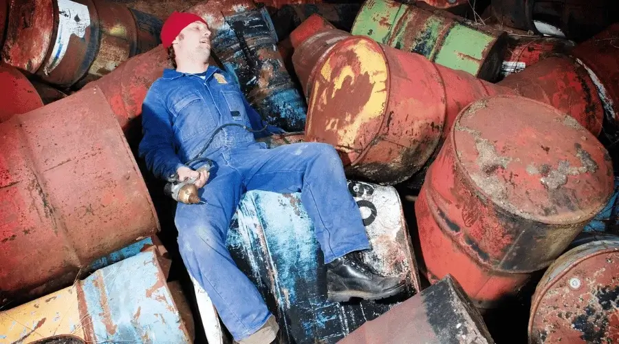 man lying on rusting oil barrels