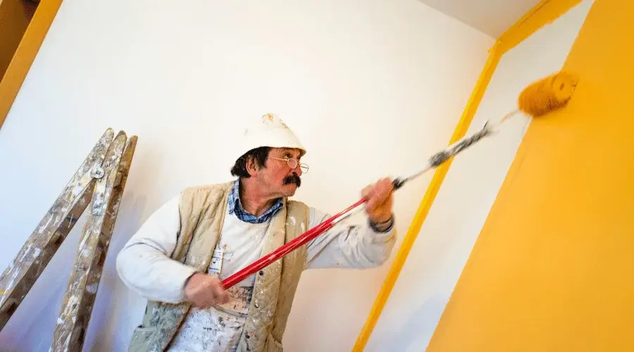 person painting wall with extended roller paints